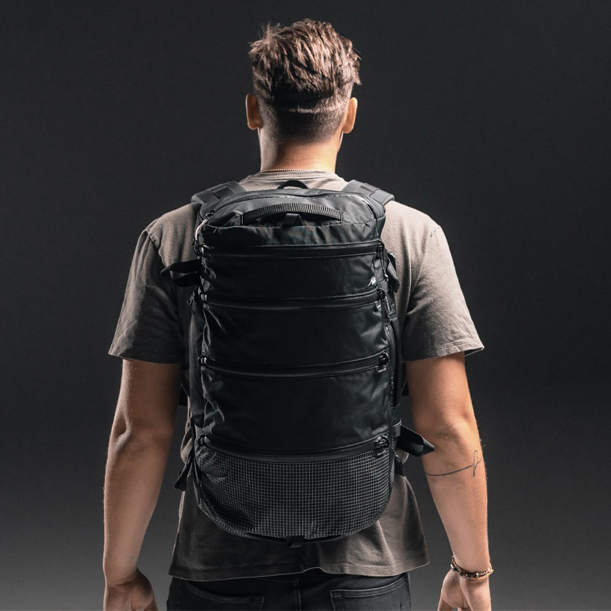 Person wearing a grey Matador Seg28
 backpack against a dark background