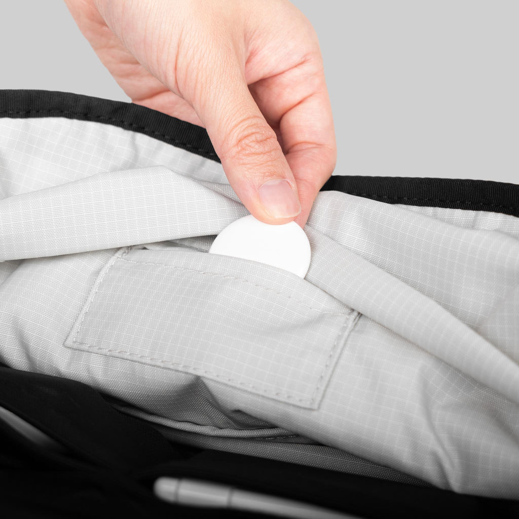 Person placing AirTag on special sleeve in Toshi Sling